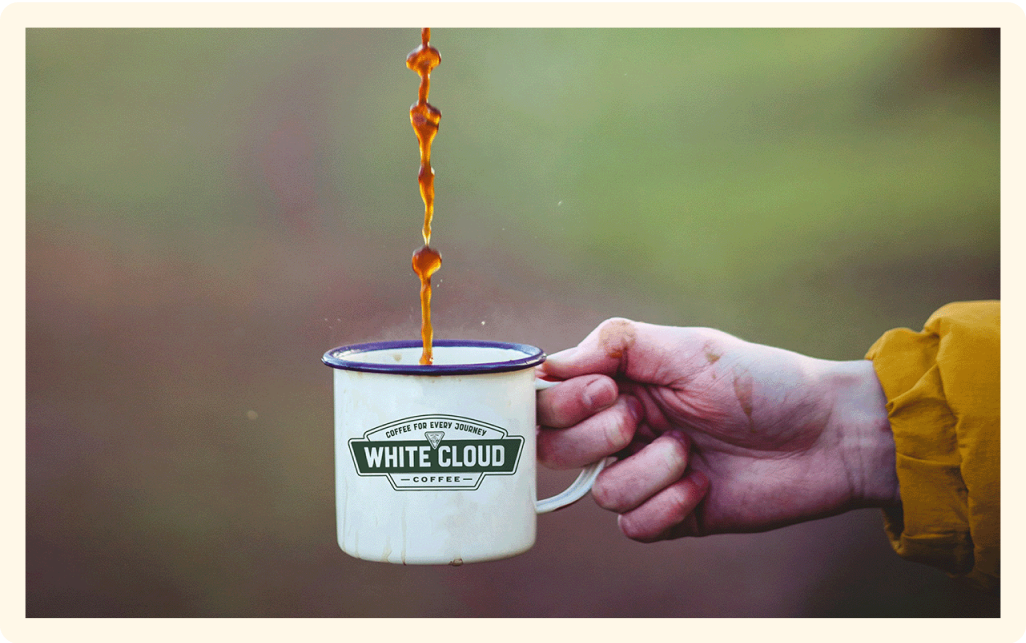 Coffee poured into White Cloud Coffee enamel camp mug held outdoors